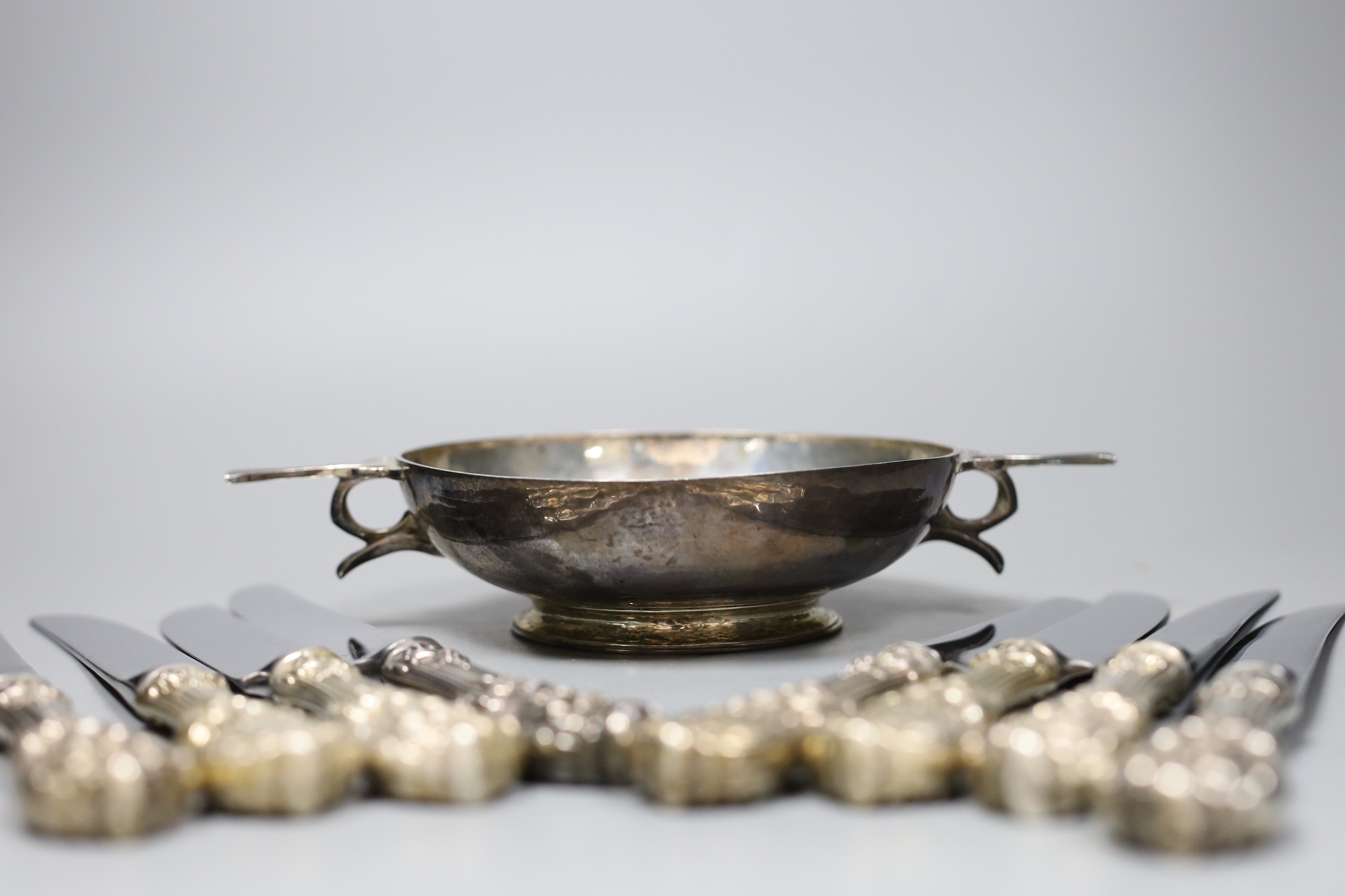 A George V silver porringer, with planished decoration, London 1910, 22cm, 247 grams and eight Reed and Barton table knives with plated handles
